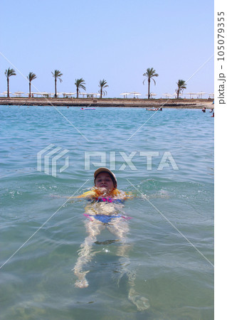 Little girl relaxing in sea lying on waves on summer holidays Little girl relaxing in sea lying on waves on summer holidays 105079355