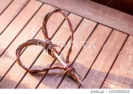 Selfmade wooden heart on the brown vintage wooden background in sunbeams. Selfmade wooden heart on the brown vintage wooden background in sunbeams. 105080826