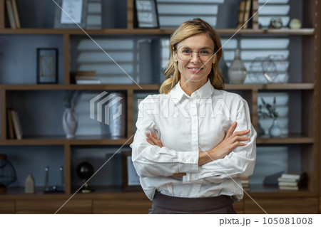 Portrait of mature experienced female boss, senior woman smiling and looking at camera with crossed arms, business woman in business shirt, financier inside office successful. 105081008