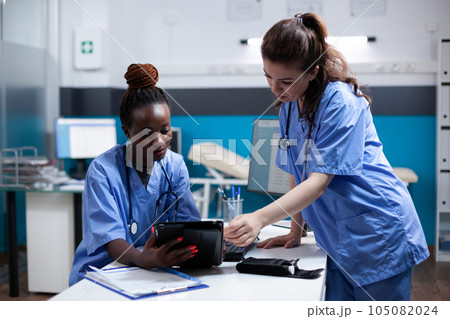 Diverse medical healthcare staff team looking at digital tablet screen in modern professional clinic office. African american nurse comparing data with coworker in hospital workplace Diverse medical healthcare staff team looking at digital tablet screen in modern professional clinic office. African american nurse comparing data with coworker in hospital workplace 105082024