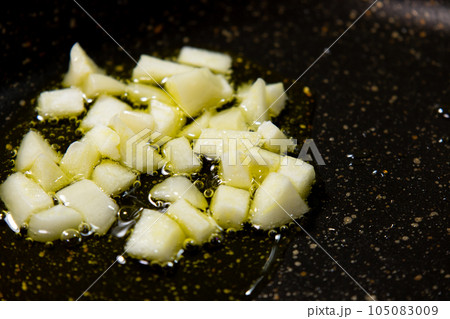 にんにく(粗みじん切り)をオリーブオイルで炒める調理シーン。 105083009