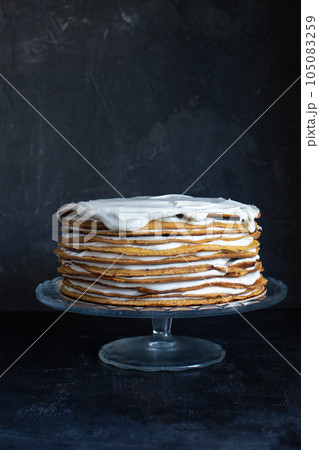 a whole round honey cake on a stand against a dark background 105083259