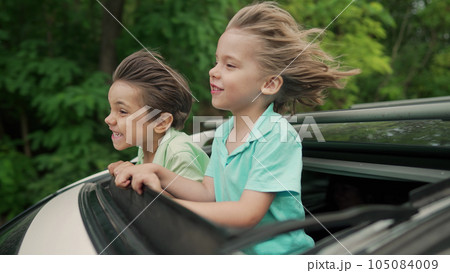 Adorable happy little boys children in open car sunroof during road trip, summer 105084009