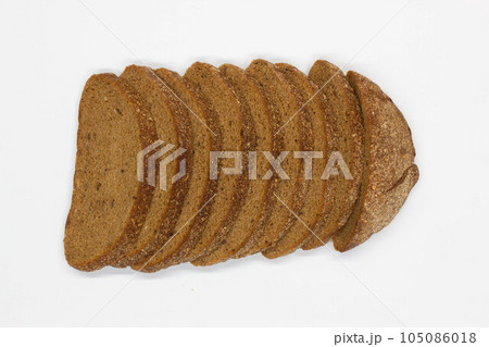 Sliced black bread. Dark rye bread with cumin cut into even pieces on a white background. Wheat black bread on the table. Isolated. Bran from grain. Healthy food. Vegetarian food. Ecological friendly 105086018