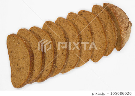 Sliced black bread. Dark rye bread with cumin cut into even pieces on a white background. Wheat black bread on the table. Isolated. Bran from grain. Healthy food. Vegetarian food. Ecological friendly 105086020