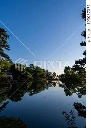 夜明けの兼六園霞ヶ池に朝日が射し込み美しい水鏡の風景｜石川県金沢市 105087375