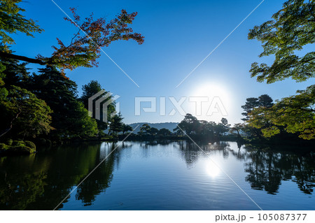 夜明けの兼六園霞ヶ池に朝日が射し込み美しい水鏡の風景｜石川県金沢市 105087377