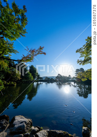 夜明けの兼六園霞ヶ池に朝日が射し込み美しい水鏡の風景｜石川県金沢市 105087378