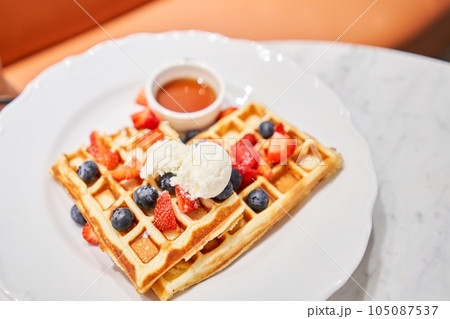 Classic Viennese waffles with ice cream, berries and Maple syrup. Breakfast in cafe. Table in the restaurant. 105087537