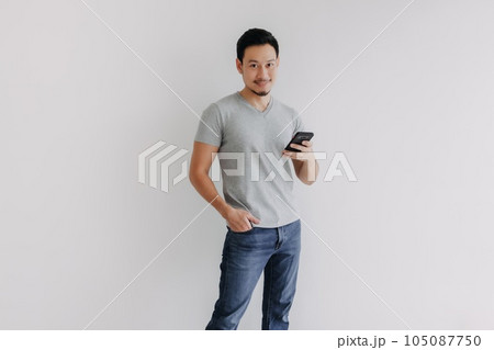 Happy handsome man in jeans using smartphone isolated on white background. 105087750