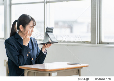 放課後に学校の教室で鏡を見ながらニキビ・肌荒れに悩む高校生・女子高生 放課後に学校の教室で鏡を見ながらニキビ・肌荒れに悩む高校生・女子高生 105088776