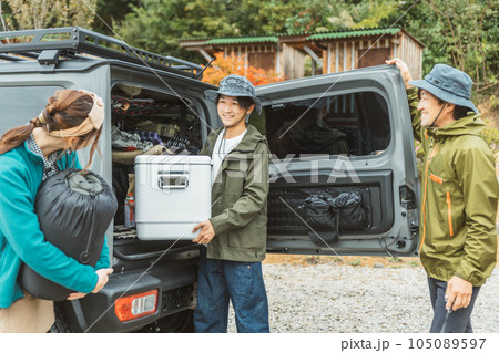 秋冬のアウトドア・キャンプ場にキャンプに来て荷物を運ぶ仲間達（男女・アジア人） 105089597