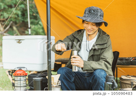 キャンプ場でソロキャンプする若い男性キャンパー（コーヒーミル） 105090483
