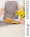 stack of classic round bisquits on a kitchen rack. crispy cookies made by teenager boy in apron. teen guy showing his own pastry ready to eat.  105090552