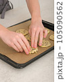 teenager boy's hands making american chocolate chip cookies at home. vertical shot of young chef hands with baking sheet. 105090562