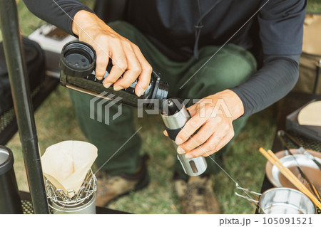 キャンプ場でコーヒーミルにコーヒー豆を入れる男性キャンパー キャンプ場でコーヒーミルにコーヒー豆を入れる男性キャンパー 105091521