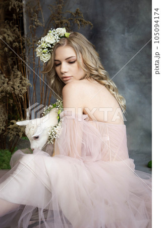 A young blonde woman in an airy pink dress with a white kid. Spring portrait of a woman. 105094174