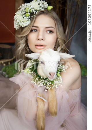 A young blonde woman in an airy pink dress with a white kid. Spring portrait of a woman. 105094175