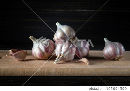 Garlic cloves and onions on a wooden cutting board before adding to food. Copy space. The idea of cooking spicy Asian food with garlic. Garlic cloves and onions on a wooden cutting board before adding to food. Copy space. The idea of cooking spicy Asian food with garlic. 105094590
