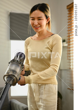 Smiling Asian housewife vacuuming and wiping dirty on the floor in living room. House cleaning and housework concept 105095107