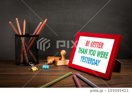 Be Better Than You Were Yesterday. Picture frame with text on wooden office table Be Better Than You Were Yesterday. Picture frame with text on wooden office table 105095421