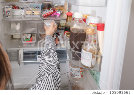 【冷蔵室からタッパを取り出す主婦】 105095665