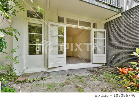 the outside of a house with an open door and some plants growing in the front yard, on a sunny day the outside of a house with an open door and some plants growing in the front yard, on a sunny day 105096740