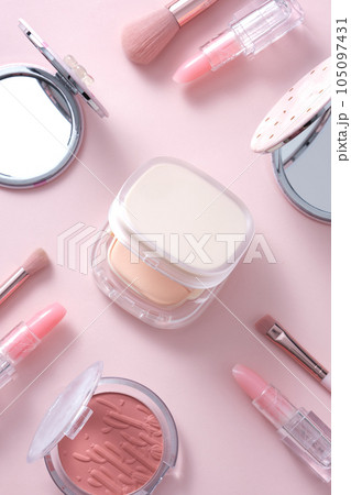 Concept of different women's accessories, different types of cosmetics for makeup: pressed powder, blush, lipstick and brush decorated on a pastel pink background.  105097431
