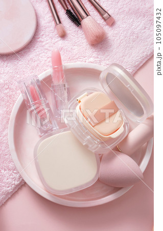 Photo for cosmetic advertising, makeup with cute concept. Powder, cushion, sponge, lipstick and powder brush decorated on round plated on pink background. Photo for cosmetic advertising, makeup with cute concept. Powder, cushion, sponge, lipstick and powder brush decorated on round plated on pink background. 105097432
