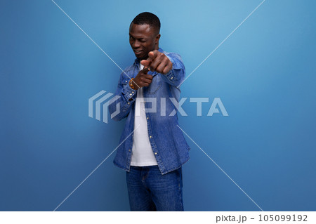 young attractive african man dressed in a denim jacket and t-shirt shows his hand at the camera on young attractive african man dressed in a denim jacket and t-shirt shows his hand at the camera on 105099192