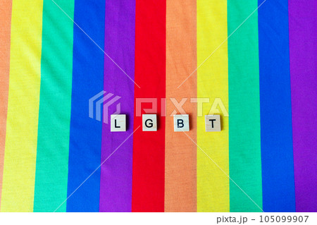 LGBT community, bright rainbow flag, wooden lettering. The rights of all people on the planet, hands in the frame, vertical photo. 105099907