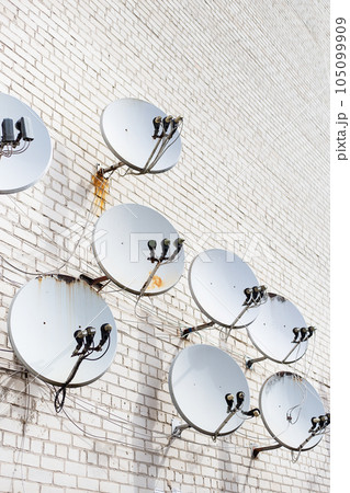 Mesh satellite television antenna for communication and the Internet. There are a lot of antennas on the wall of the house. 105099909