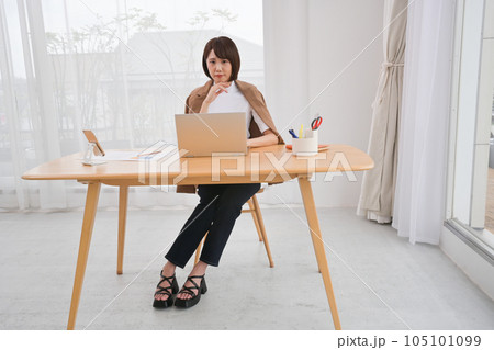 屋内の机でノートパソコンの操作をする若い女性 105101099
