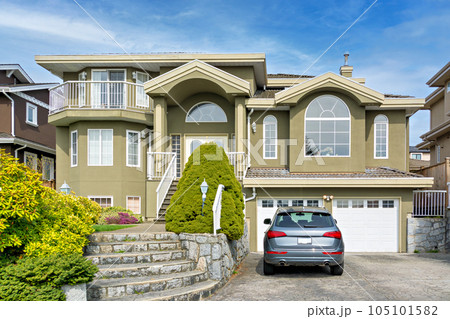 Luxury residential house with a car parked in front on cloudy day Luxury residential house with a car parked in front on cloudy day 105101582