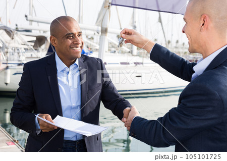 Latin American men with documents and keys near the yachts in the port 105101725