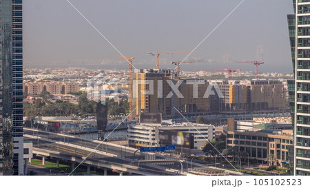Construction site around Dubai water canal with many cranes aerial timelapse. 105102523