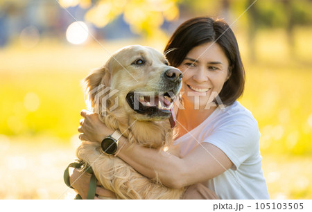 Girl with beautiful golden retriever dog, portrait on a blurred background 105103505