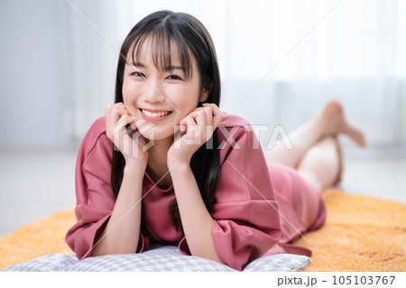 カーペットに寝転んでくつろぐ若い女性 105103767