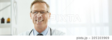 Cheerful male doctor sitting at the table with laptop in clinic Cheerful male doctor sitting at the table with laptop in clinic 105103969