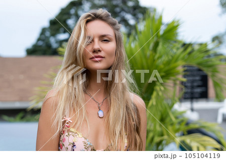 Beautiful young blonde in a top with long hair and smooth clean soft skin, natural beauty, daylight, pendant on neck accessory, posing with palm leaf Beautiful young blonde in a top with long hair and smooth clean soft skin, natural beauty, daylight, pendant on neck accessory, posing with palm leaf 105104119