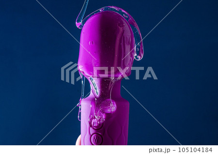 Intimate lubricant pours on a purple vibrator on a blue background. Copy space.  105104184