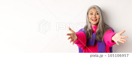 Close-up of stylish asian mature woman reaching hands forward, stretching arms for hug or hold something, smiling happy, standing over white background Close-up of stylish asian mature woman reaching hands forward, stretching arms for hug or hold something, smiling happy, standing over white background 105106957