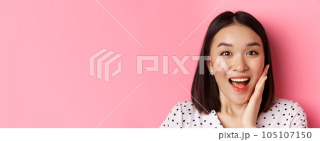 Beauty and lifestyle concept. Close-up of surprised and happy asian woman staring at camera amazed, gasping with disbelief, standing over pink background Beauty and lifestyle concept. Close-up of surprised and happy asian woman staring at camera amazed, gasping with disbelief, standing over pink background 105107150