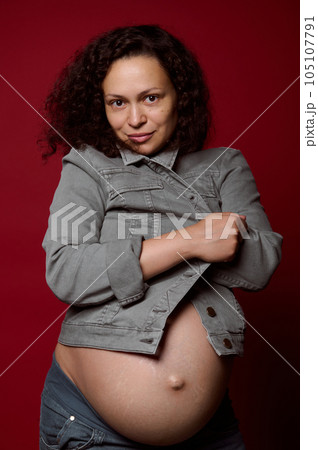 Beautiful multi-ethnic young pregnant woman with naked belly, wearing stylish casual denim blazer, looking at camera Beautiful multi-ethnic young pregnant woman with naked belly, wearing stylish casual denim blazer, looking at camera 105107791