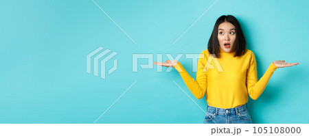 Confused and shocked asian woman dont understand, shrugging with spread hands, gasping and looking left, know nothing, standing over blue background Confused and shocked asian woman dont understand, shrugging with spread hands, gasping and looking left, know nothing, standing over blue background 105108000