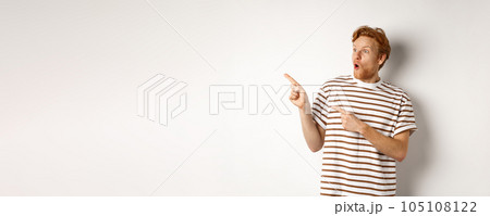 Check it out. Amazed redhead guy pointing and looking left at promotion banner, saying wow, standing over white background Check it out. Amazed redhead guy pointing and looking left at promotion banner, saying wow, standing over white background 105108122