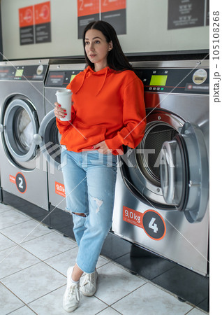 Portrait of young woman standing in the self-service public laundry. Portrait of young woman standing in the self-service public laundry. 105108268