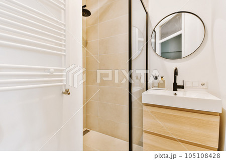 a modern bathroom with beige tile and white fixtures on the walls, along with a wooden cabinet under the sink is next to the a modern bathroom with beige tile and white fixtures on the walls, along with a wooden cabinet under the sink is next to the 105108428