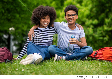 Two african american kids sitting on the grass in the park Two african american kids sitting on the grass in the park 105108548