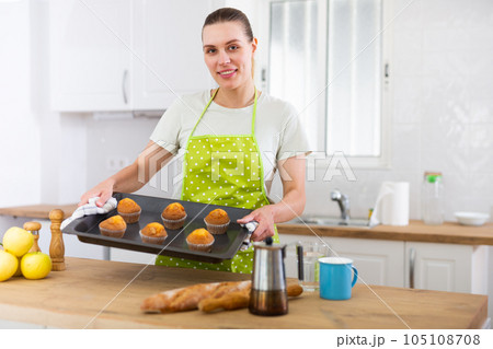 Positive woman holding baking pan with cupcakes Positive woman holding baking pan with cupcakes 105108708